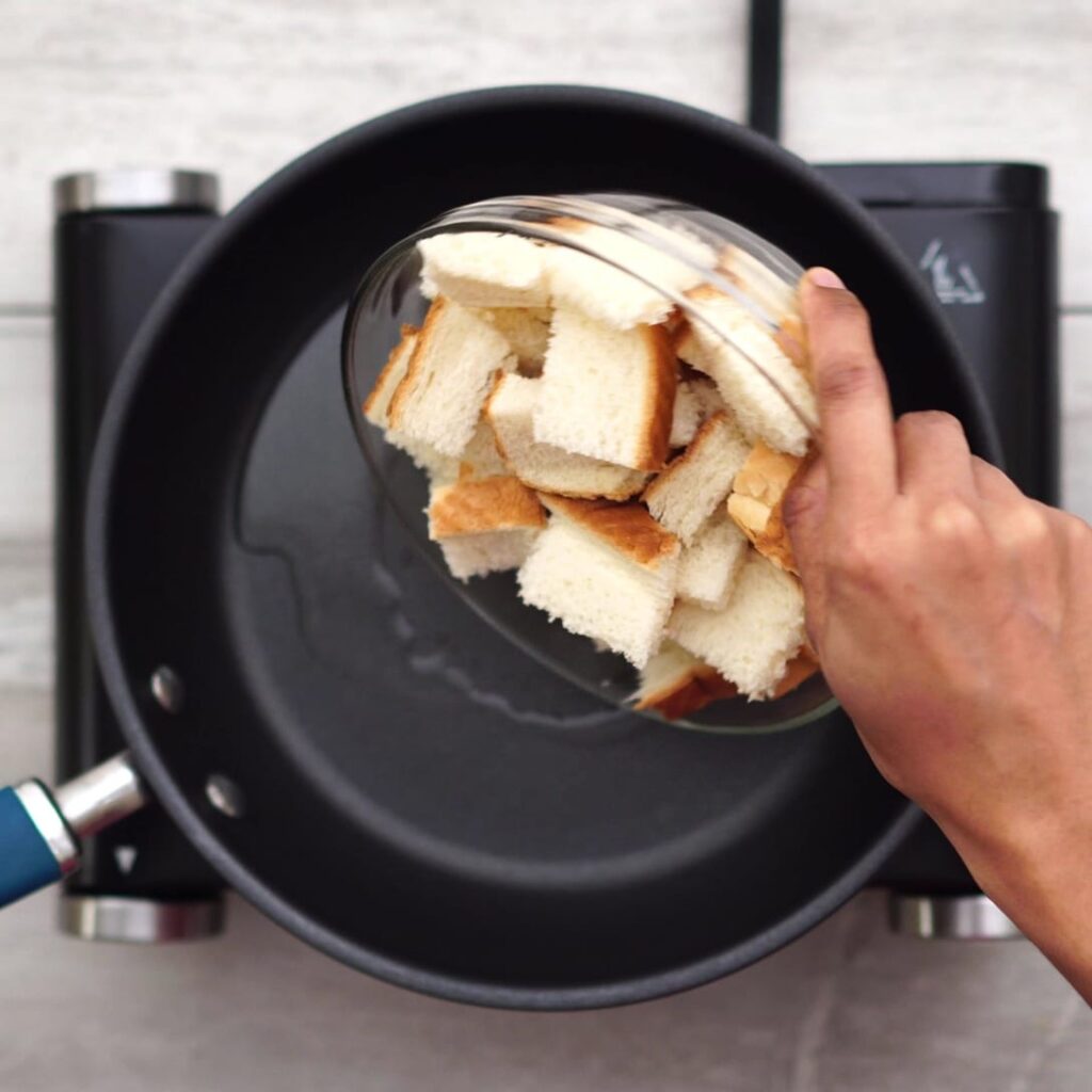 Adding bread pieces into a pan with oil