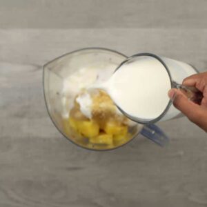 Adding fruits and Dairy free milk and yogurt along with pineapples into a jar.