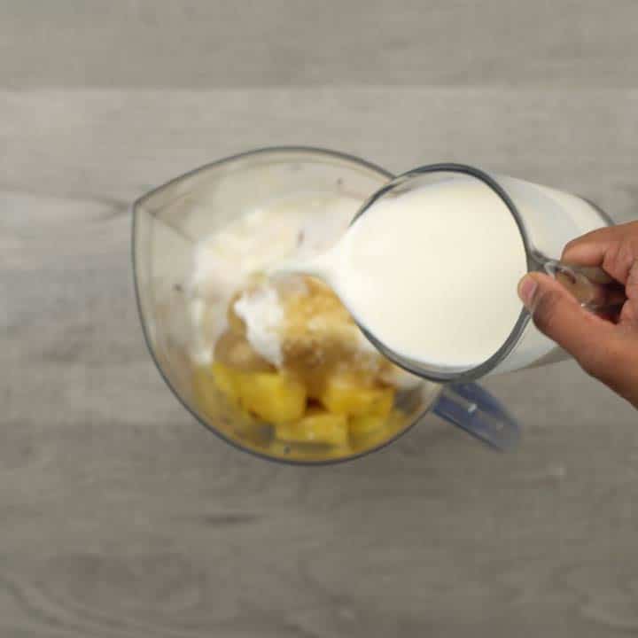 Adding fruits and Dairy free milk and yogurt along with pineapples into a jar.