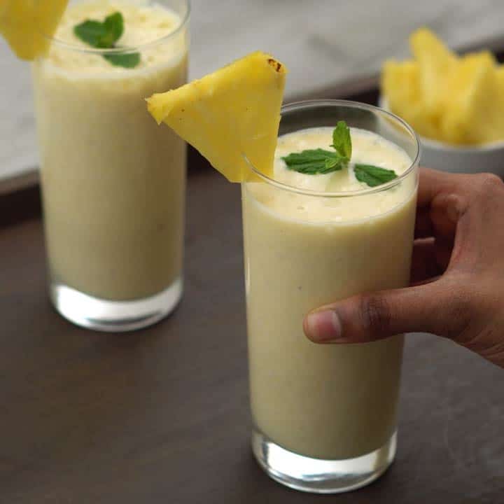 Serving healthy pineapple smoothie in a serving glass.
