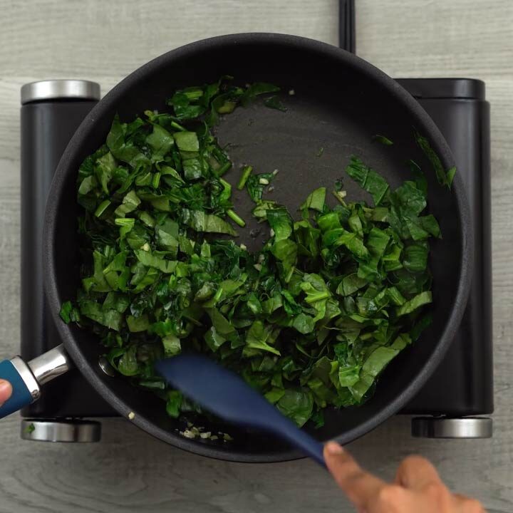 Stirring spinach until it is wilted