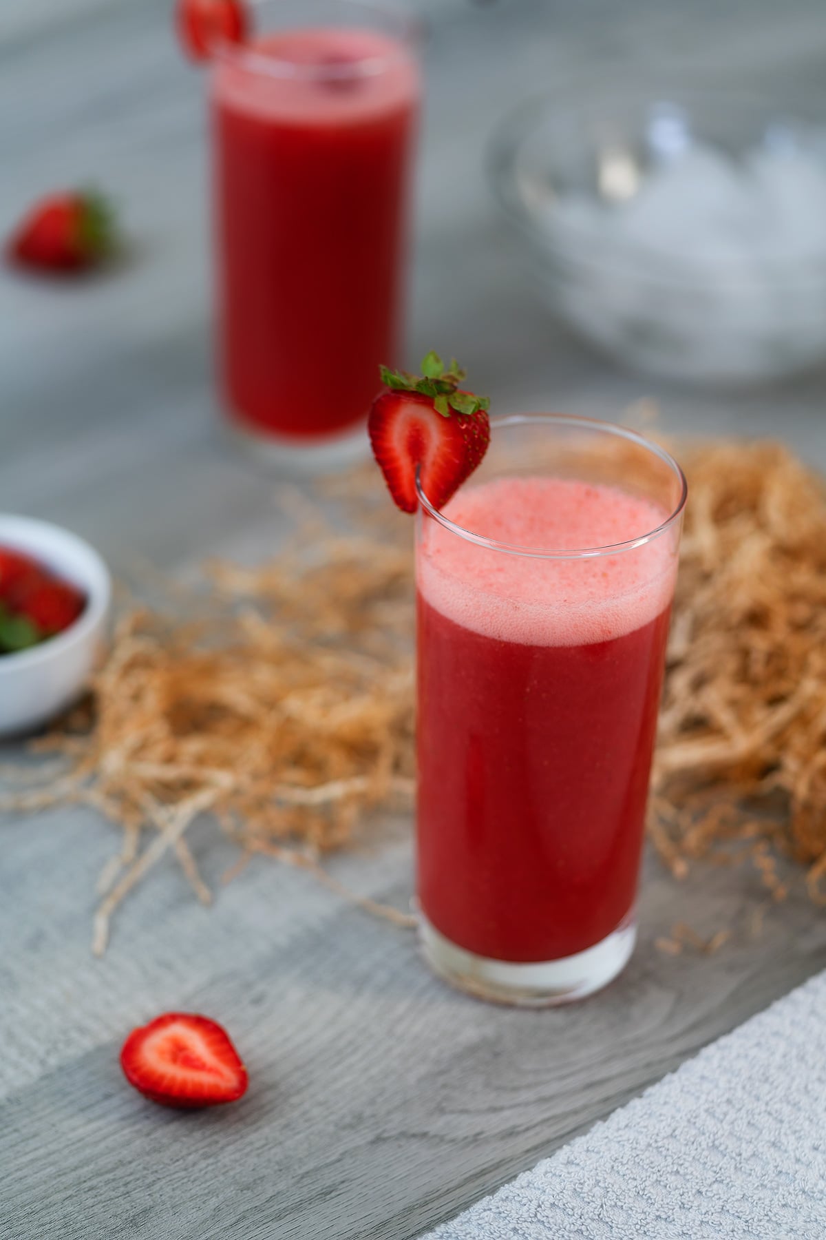 Strawberry Juice in a serving glass with strawberries around.