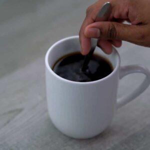 Stirring the black coffee with a spoon.