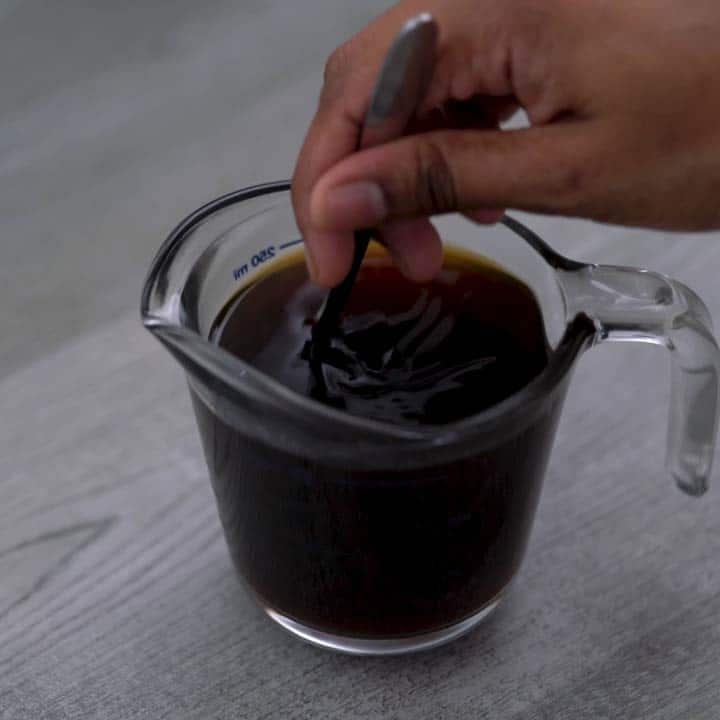 Mixing the black coffee with a spoon.