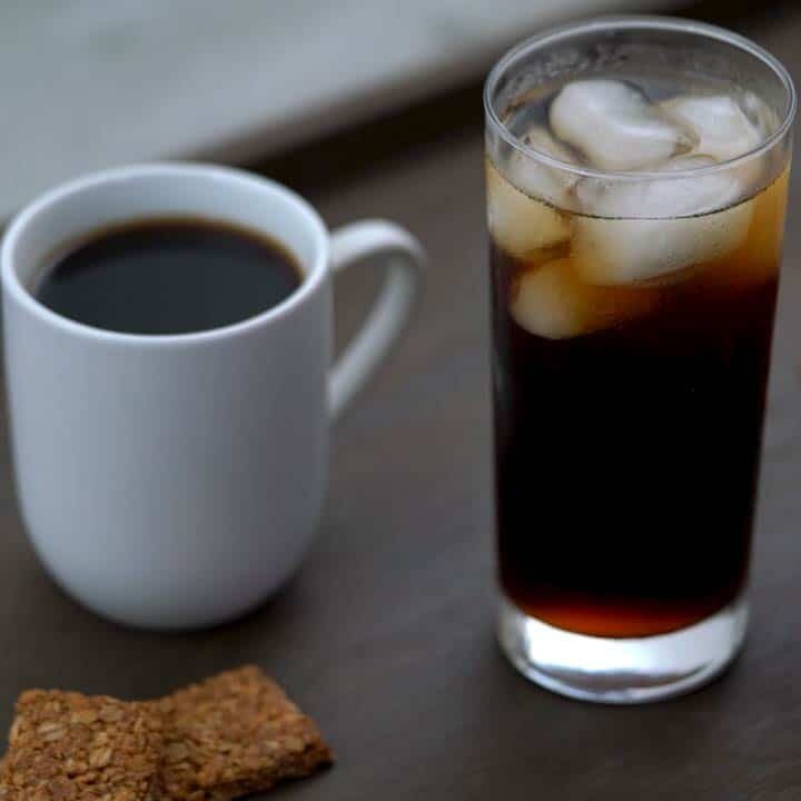 Hot and iced black coffee served in tall glass and white mug.