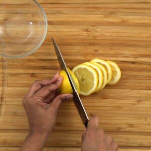 Slicing fresh lemons into circular shapes.
