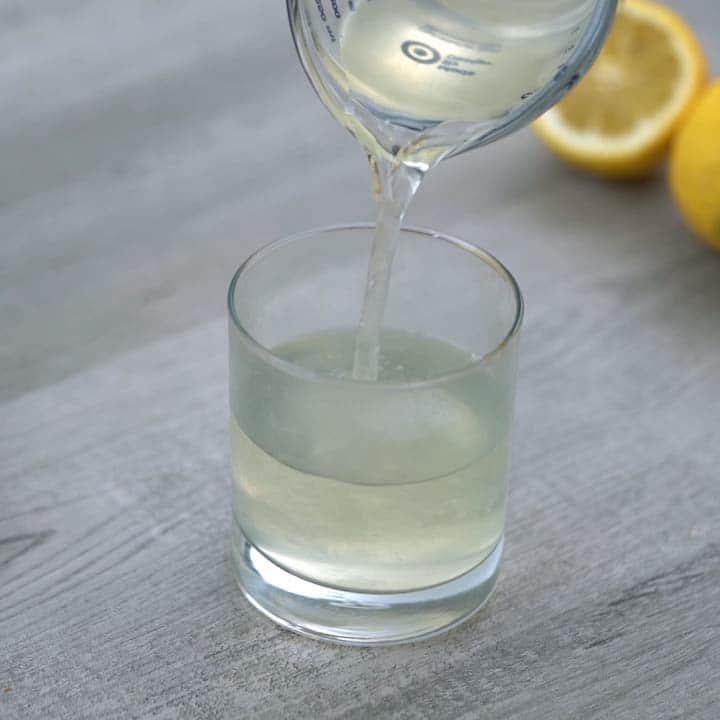 Pouring lemon ginger tea into a glass.