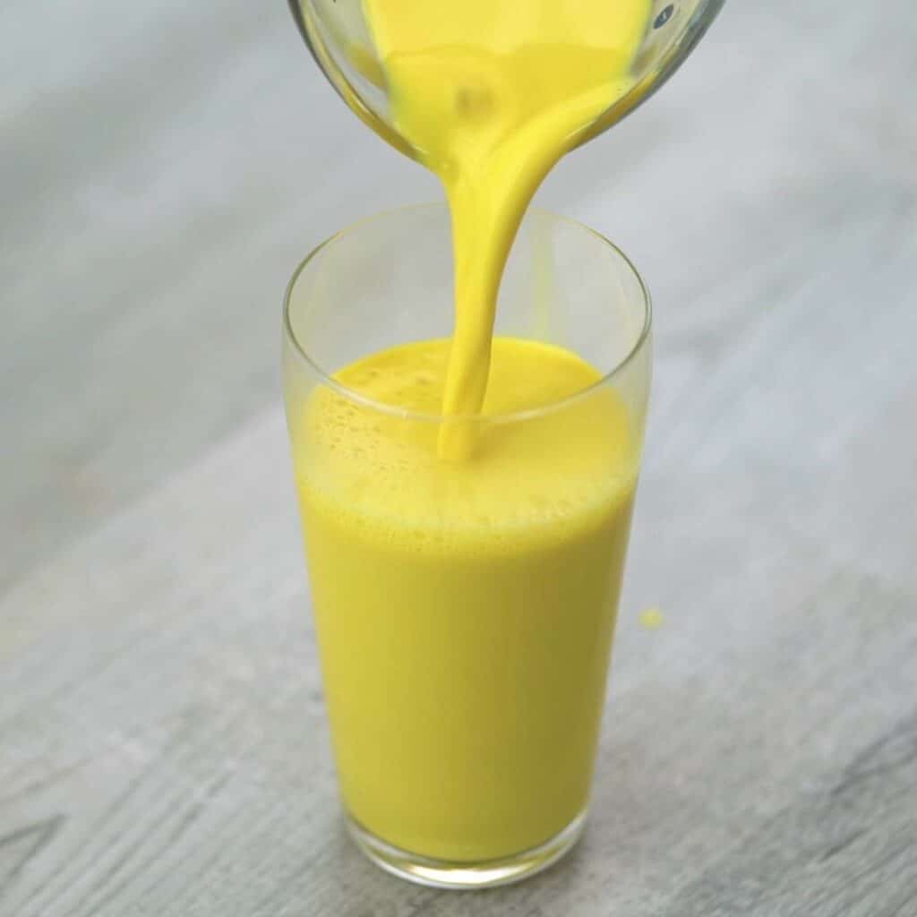 Pouring Turmeric Milk into a serving glass.