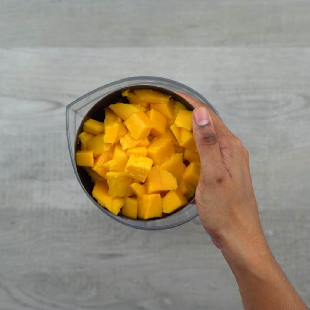 Diced ripe mango in a black bowl.