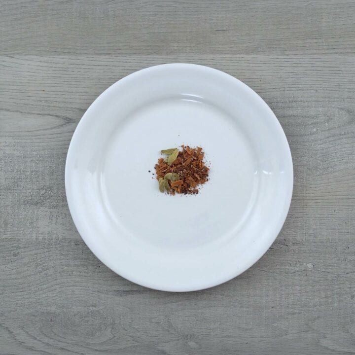 Crushed masala tea spices on a white plate.