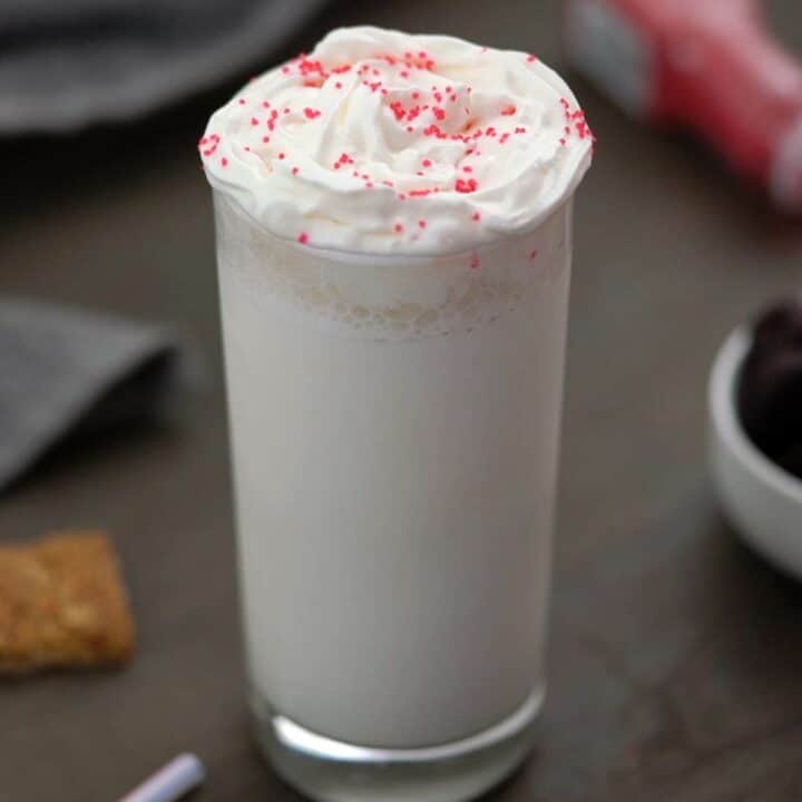 Vanilla Milkshake topped with cream and snacks around.