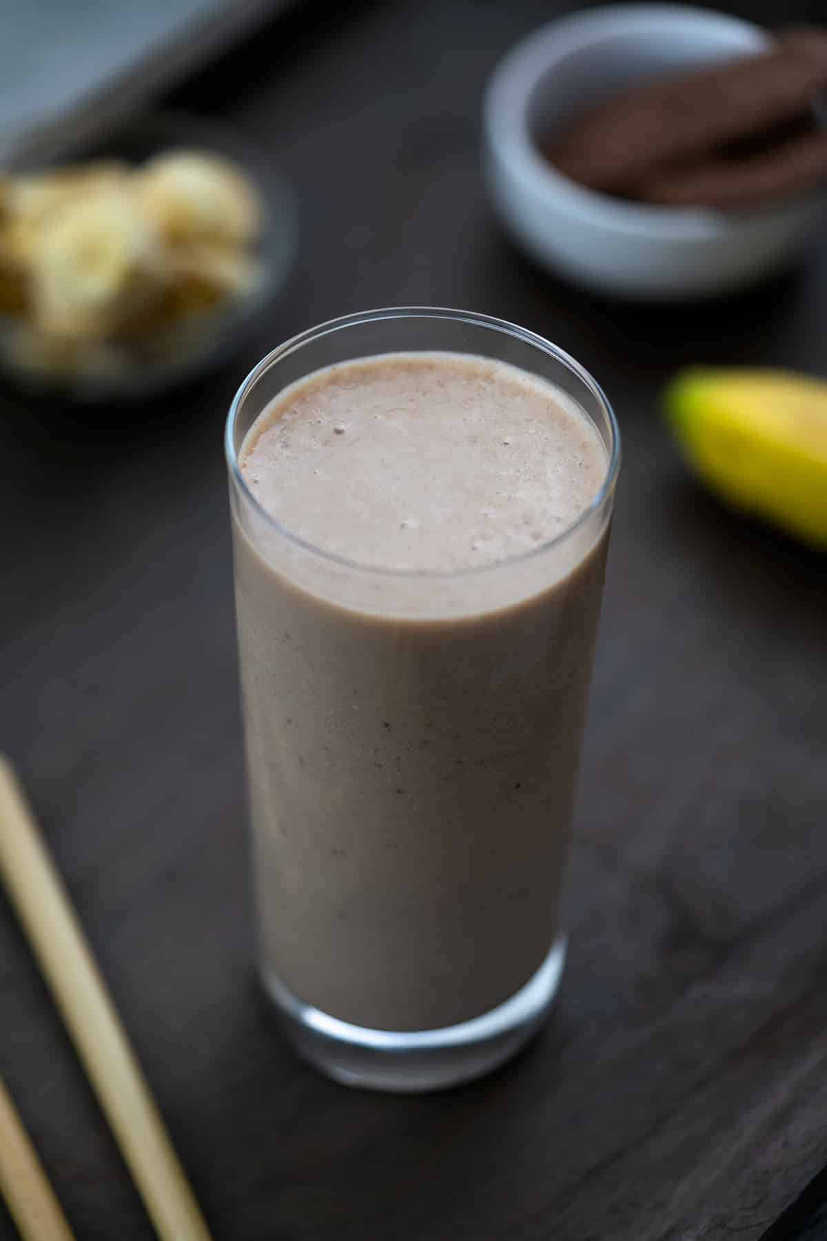 Healthy Banana Smoothie served in a glass with banana nearby.