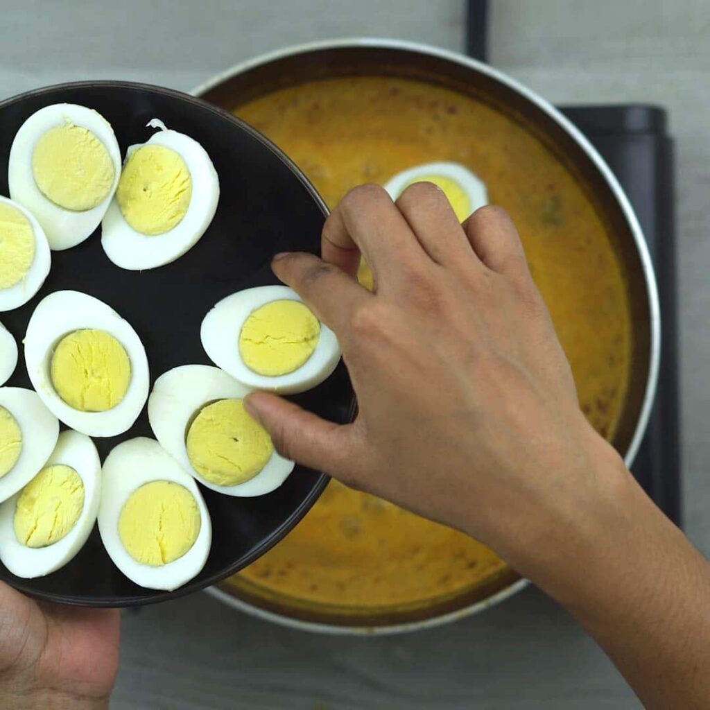 adding boiled eggs to the curry