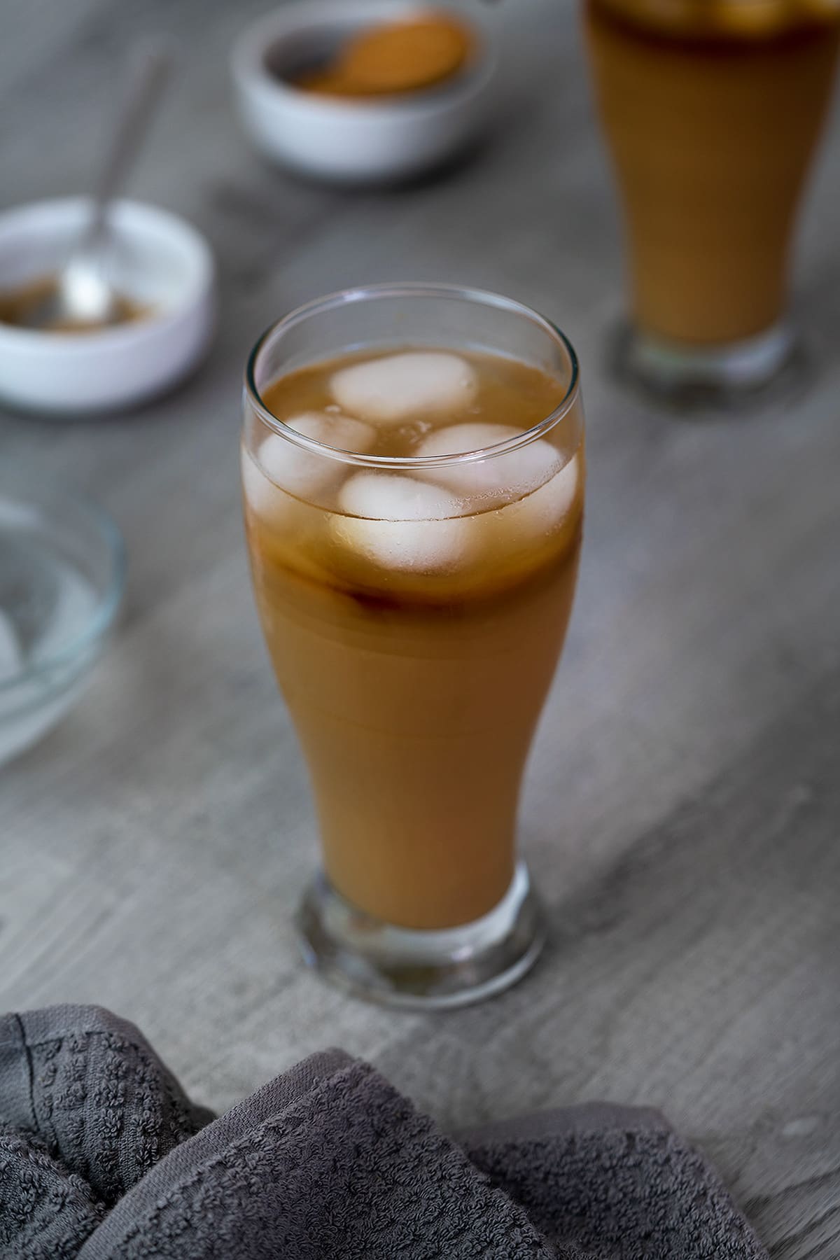 Iced coffee served in a glass with brown sugar and ice cubes nearby.