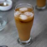 Iced coffee served in a glass with brown sugar and ice cubes nearby.