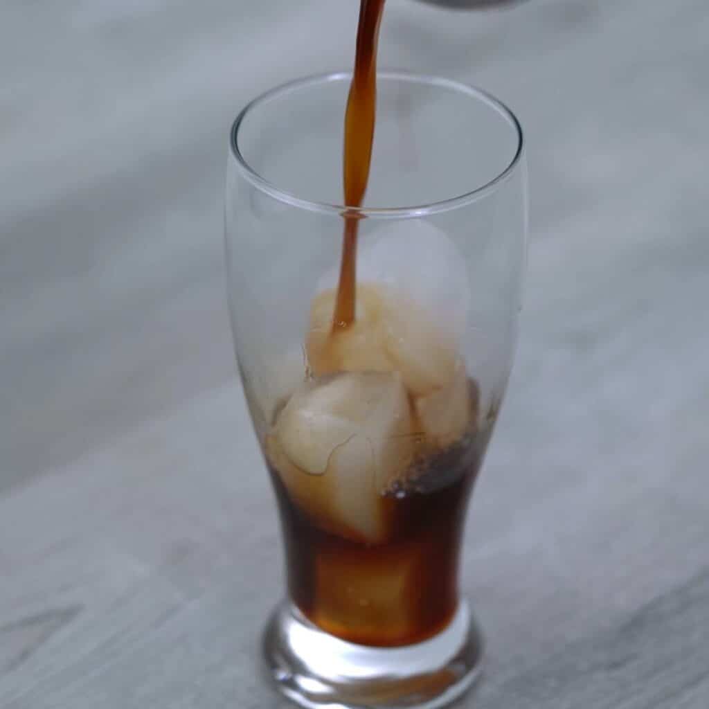 Pouring chilled coffee over ice.