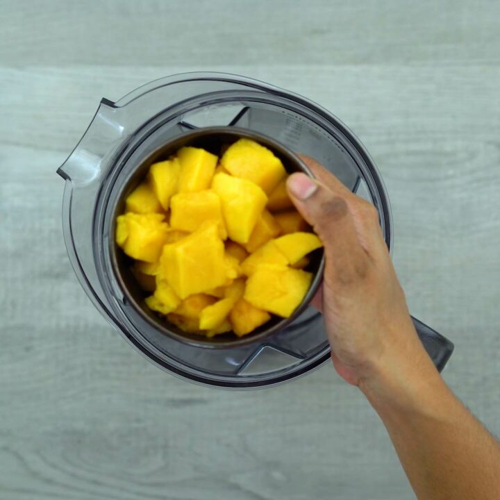 Adding mango pulp to blender.
