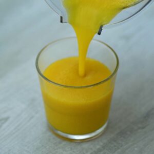 Pouring mango juice into glass.
