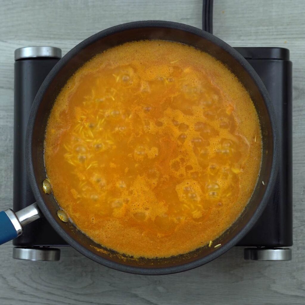 rice is cooking in tomato water mixture