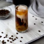 Cold brew coffee in a glass placed on a white table.