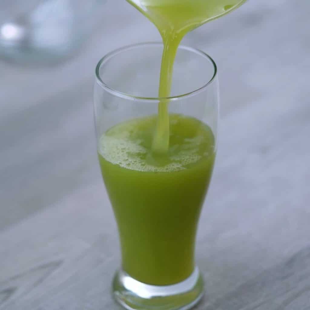 Pouring celery juice into a glass.