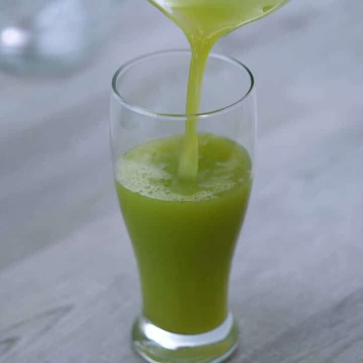 Pouring celery juice into a glass.