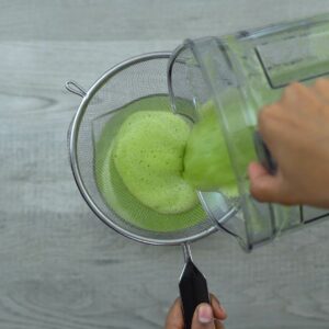 Pouring the cucumber juice with mesh strainer.