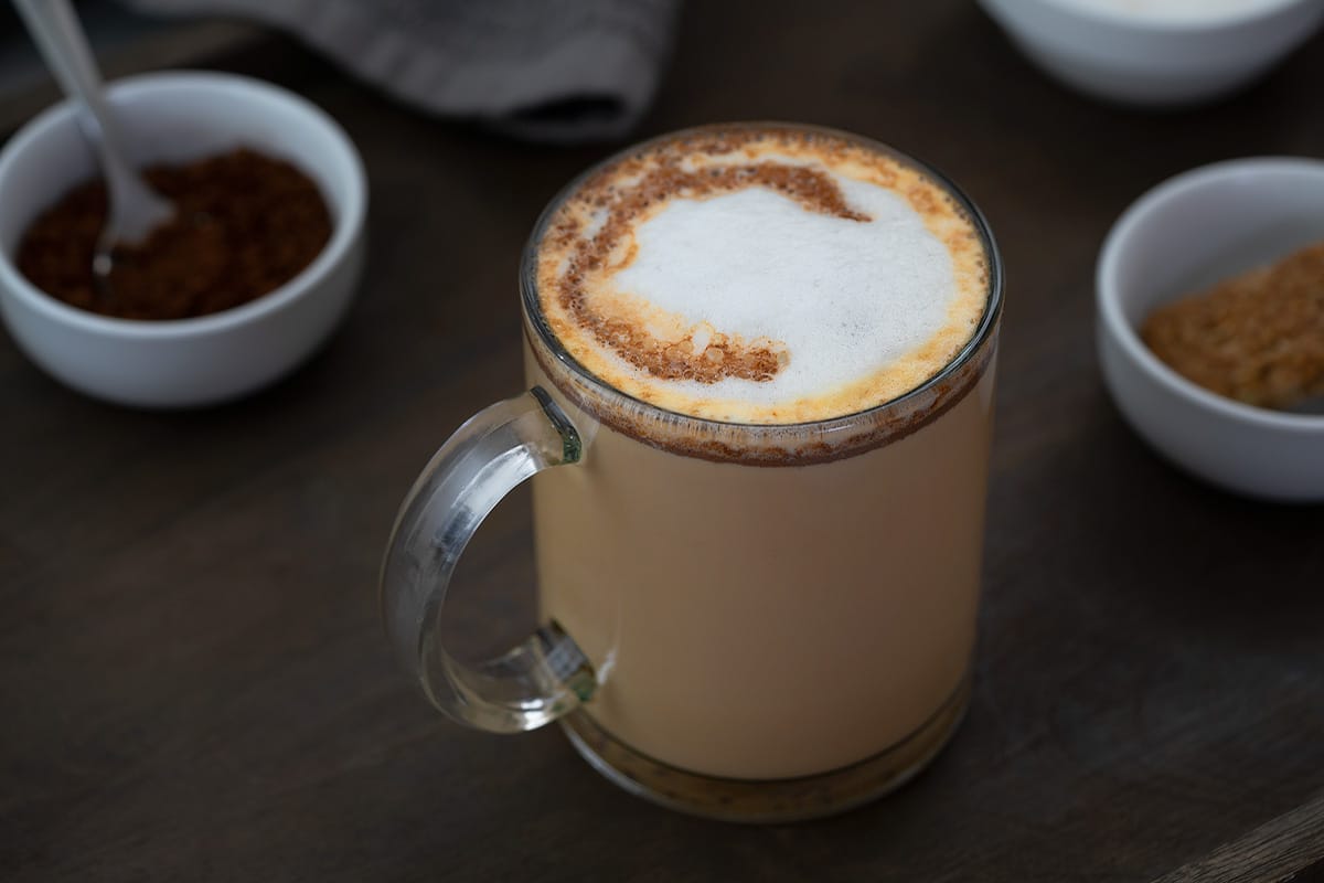 Mocha Coffee served in a glass mug with coffee powder placed in a bowl nearby.