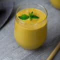 Mango Smoothie garnished with mint leaves in a serving glass.