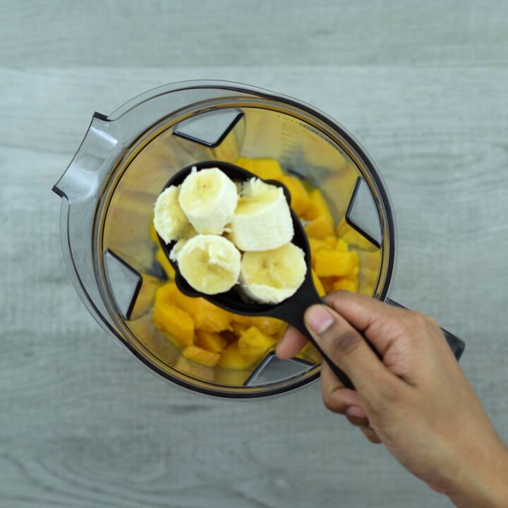 Adding Mango Smoothie ingredients into a blender.