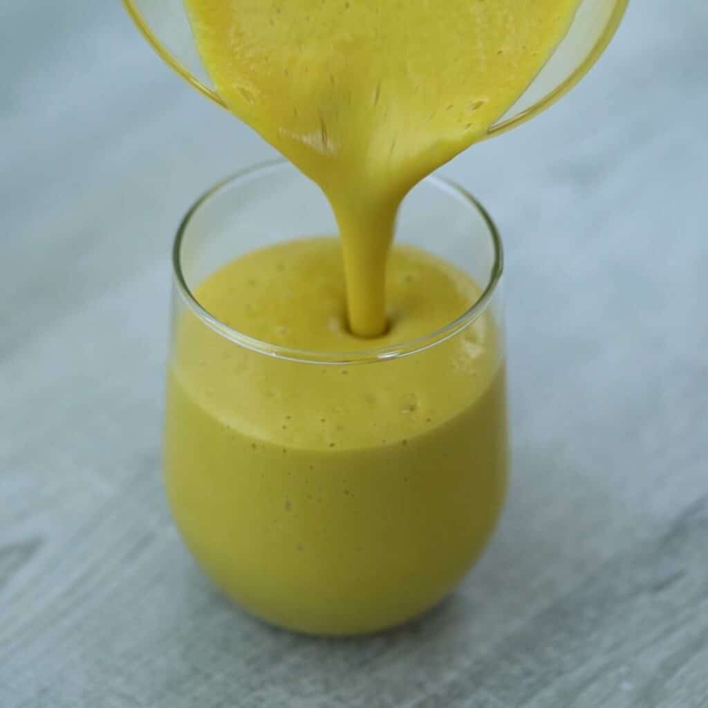 Pouring the Mango Smoothie into a glass.