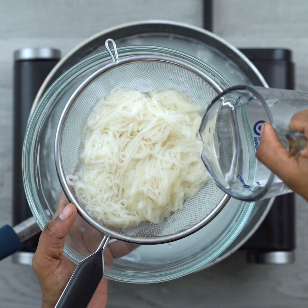 pouring water over cooked rice noodles