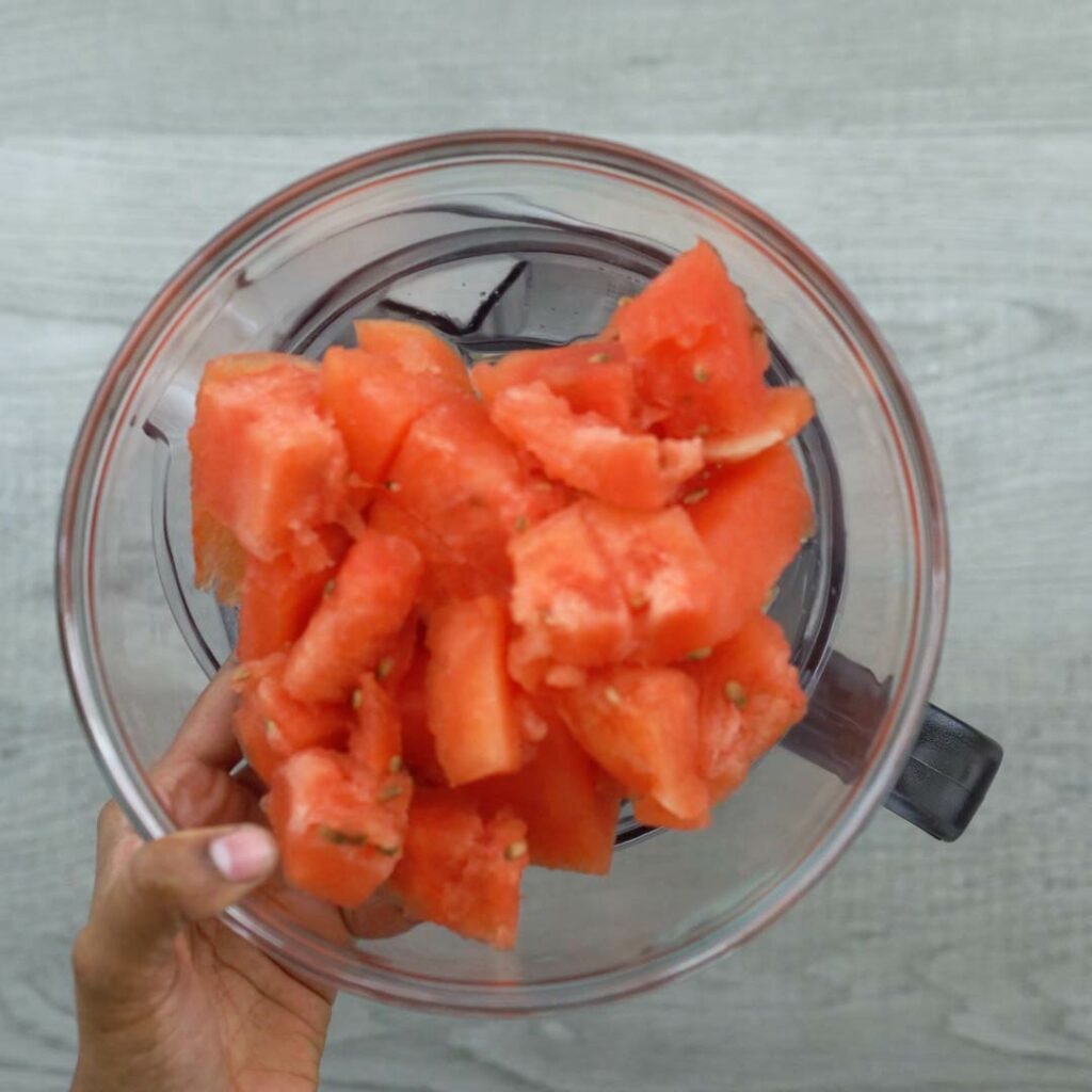 Adding watermelon to the blender.