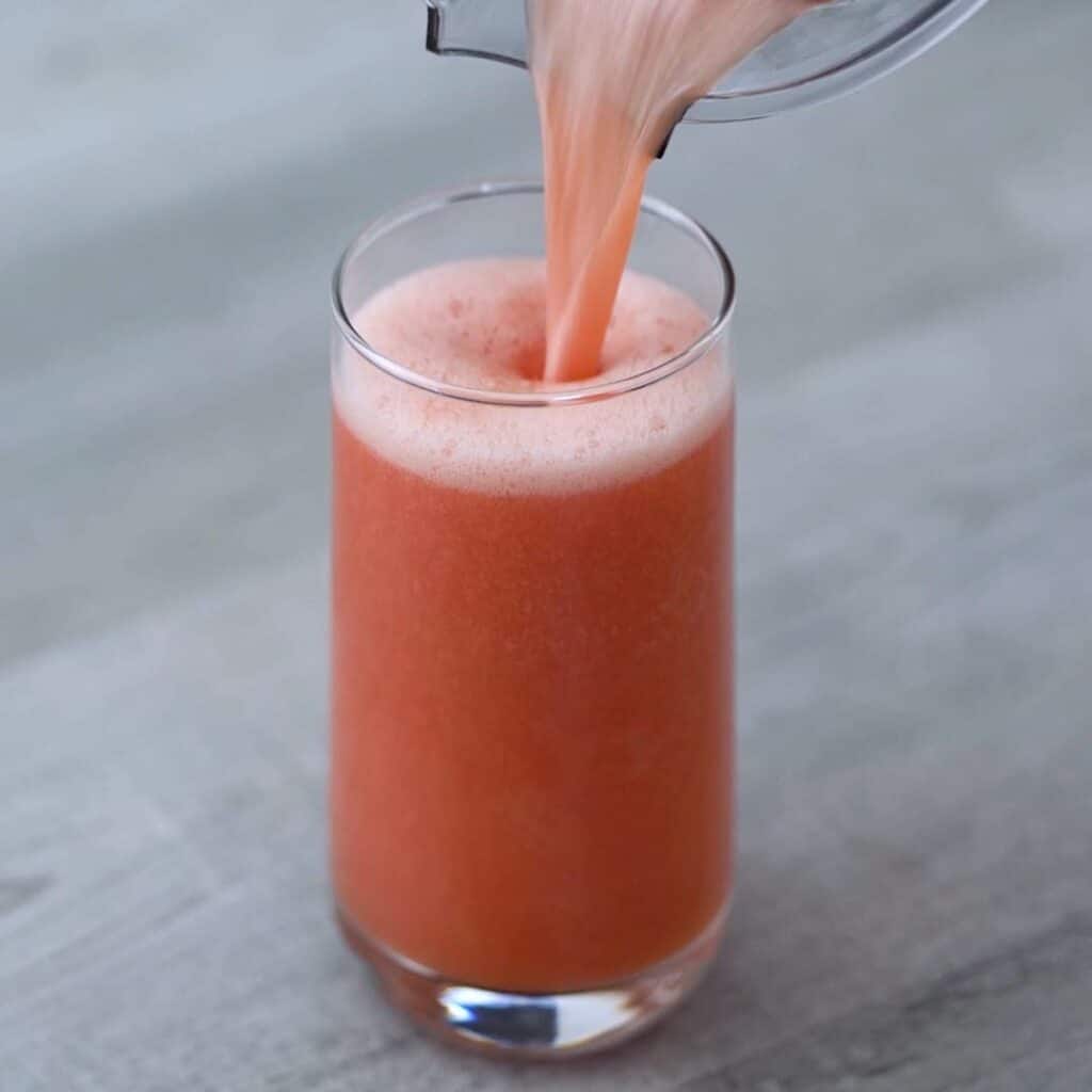 Pouring watermelon juice into a glass.