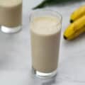 Banana Protein Shake served in a glass with banana placed nearby.