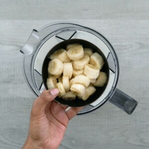 Adding banana and other ingredients to the blender.