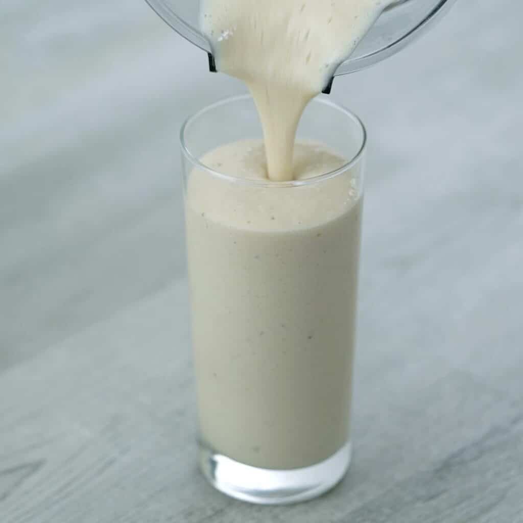 Pouring banana protein shake into the glass.