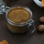 Chai Masala Powder in a jar with few spices placed nearby.
