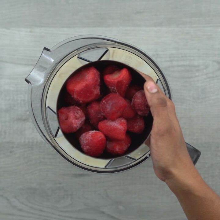 Adding strawberries, ice cream and milk into jar.