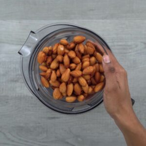 Adding soaked almonds in blender jar.