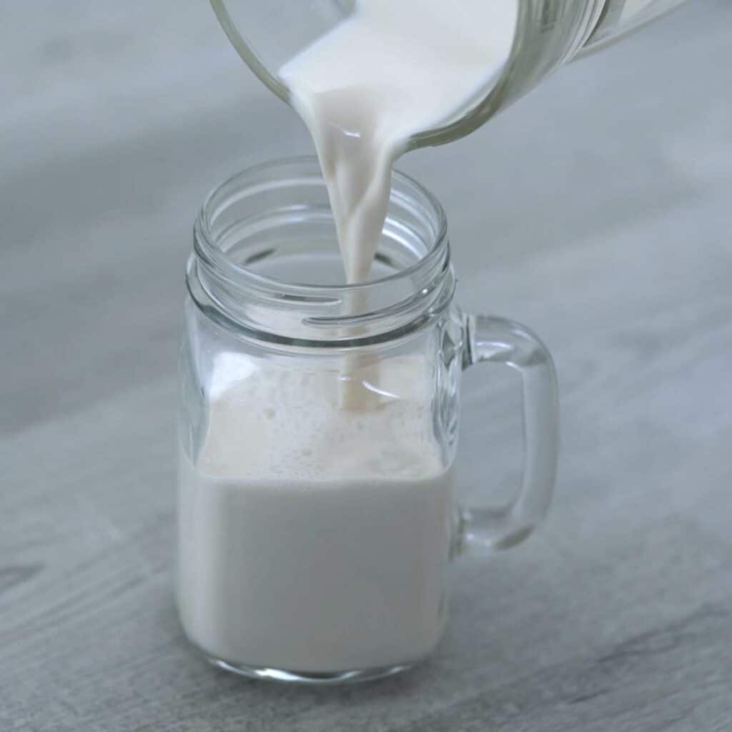 Pouring the almond milk into a serving glass.