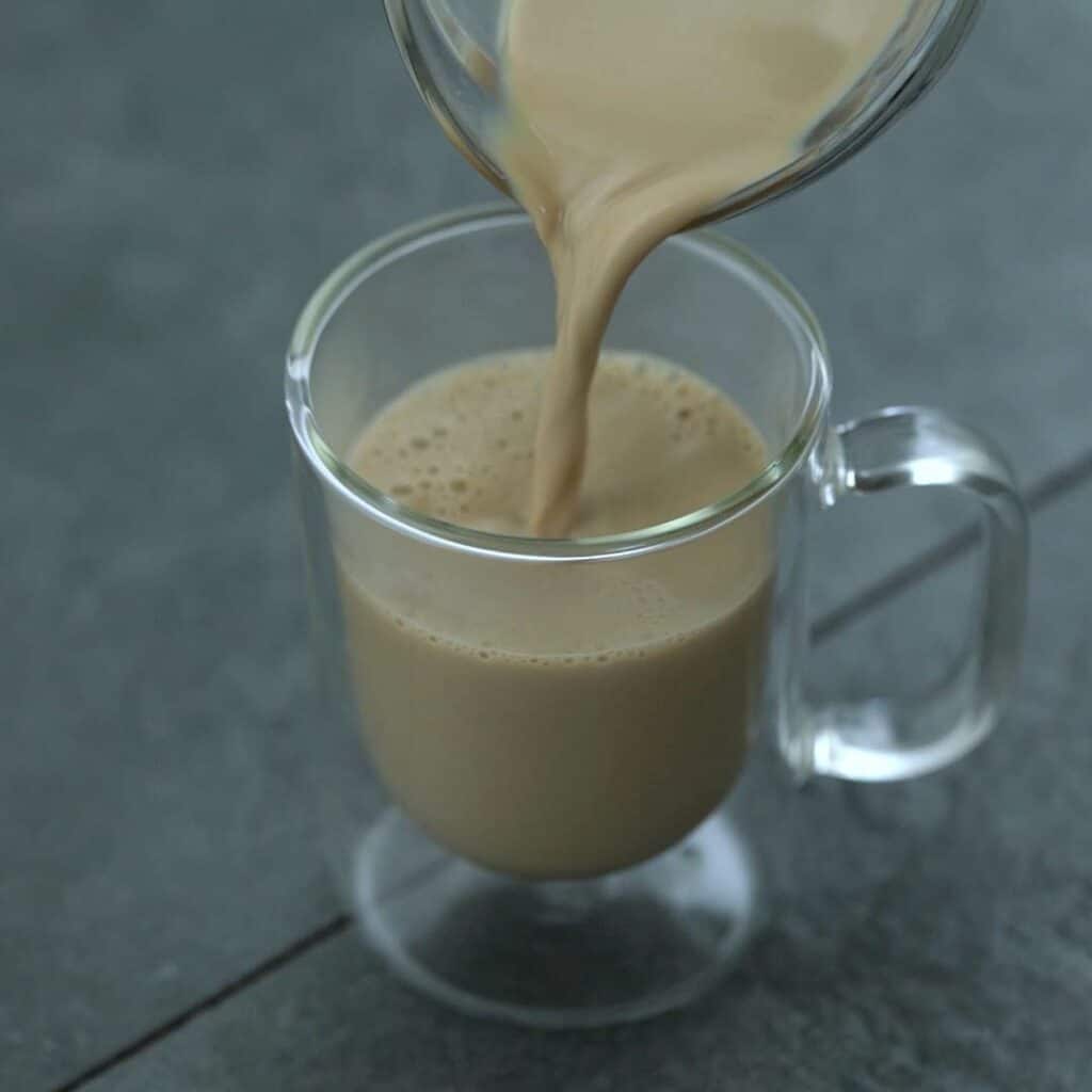 Pouring the pumpkin spice latte drink into glass.