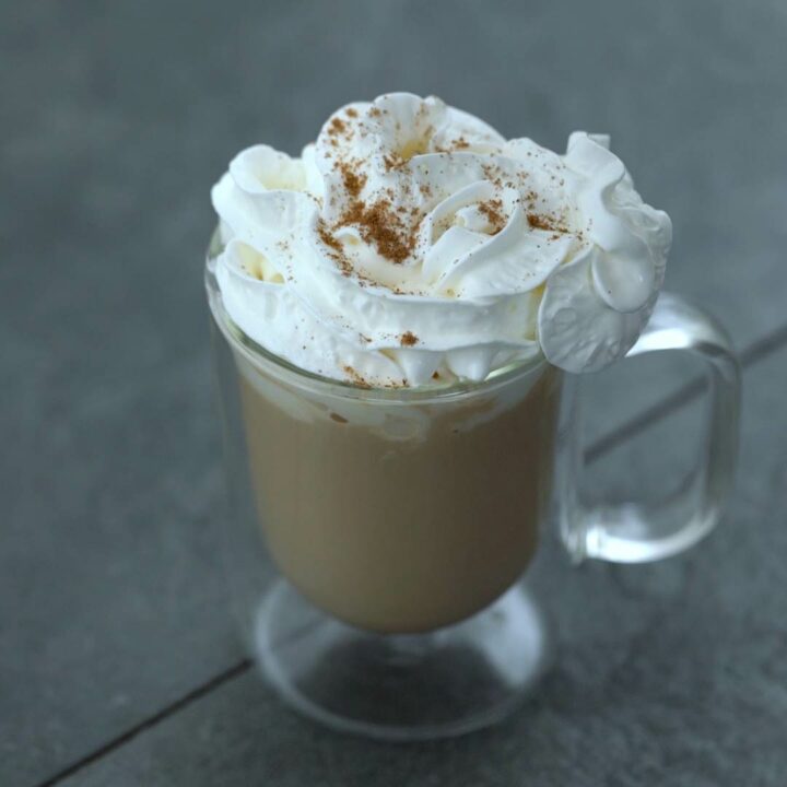 Pumpkin spice latte topped with whipped cream and spice powder.
