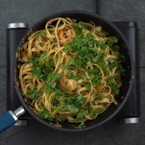 garlic butter shrimp pasta garnished with coriander leaves