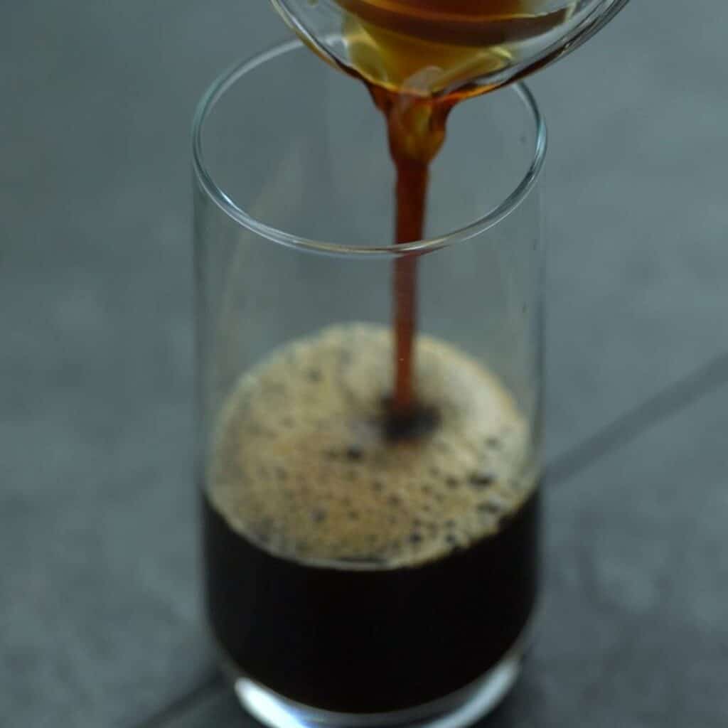 Pouring espresso coffee into a glass.