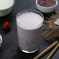 Strawberry Milk in a glass with strawberries and snacks around.