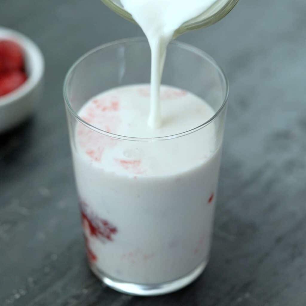 Pour cold milk into strawberry syrup.
