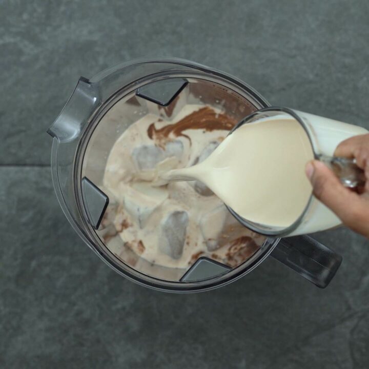 Adding hot chocolate, milk, ice cubes to the blender.