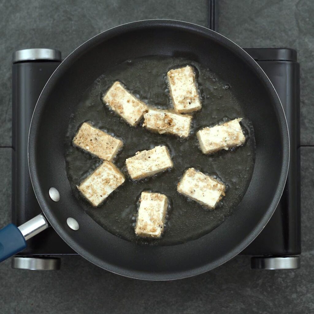 marinated tofu frying in a pan
