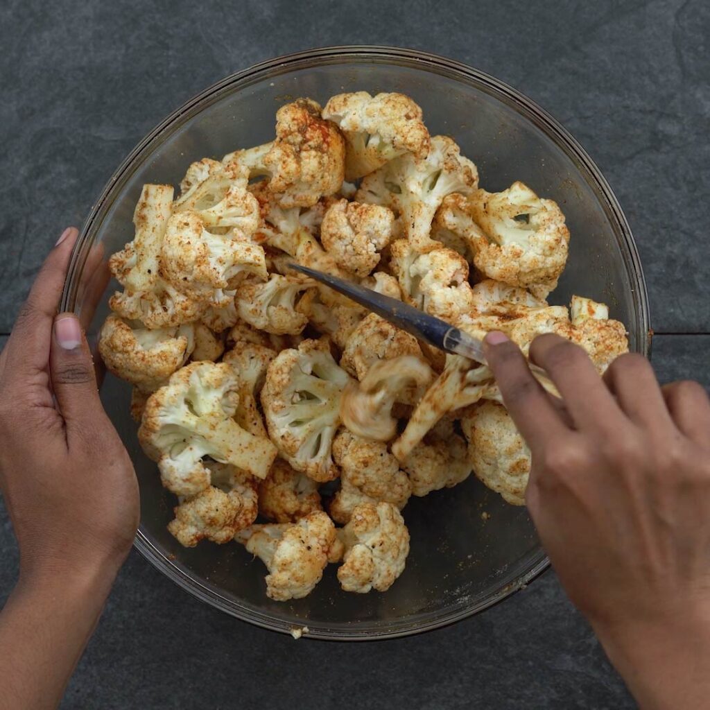 tossing the spice powders into cauliflower